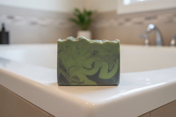 A bar of soap with green swirls, placed on a surface with a plant in the background.